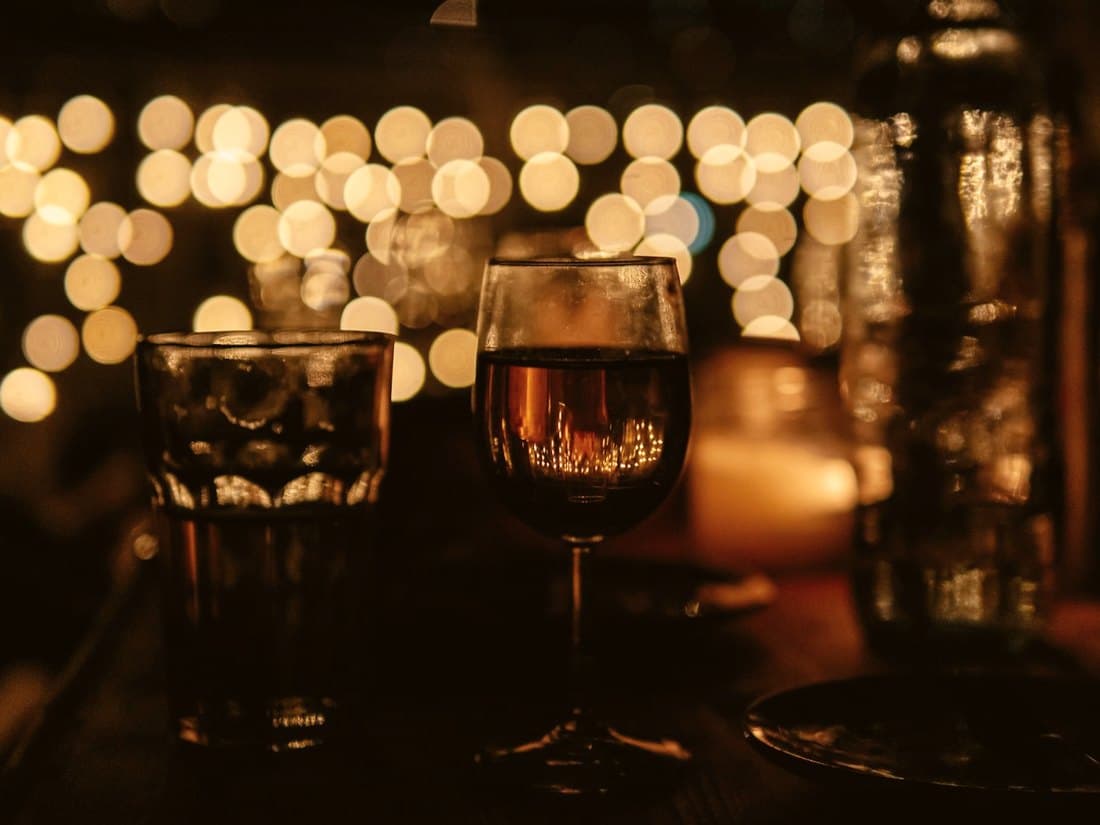 Drinks on a bar counter under warm string lights at night